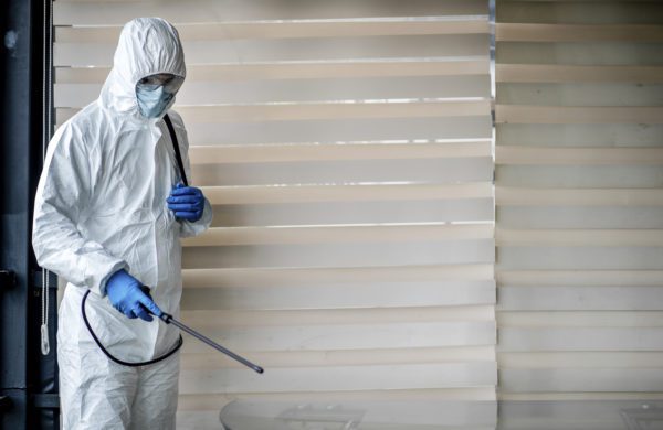 Man In Quarantine Clothes Disinfecting Room